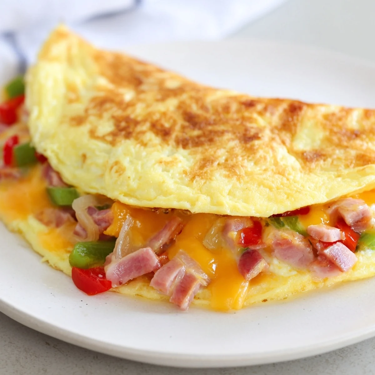 Imagine savoring this hearty Denver Omelet, filled with savory ham and a melty, cheesy filling.