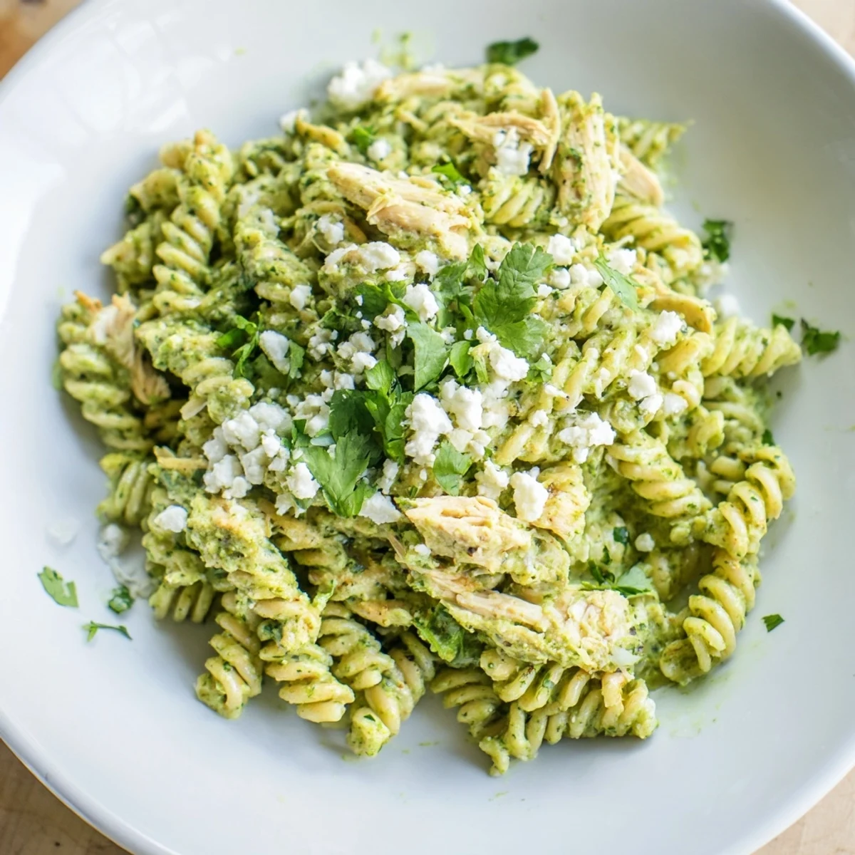 Serving of homemade cilantro lime chicken pasta with lime wedges on a rustic wooden table.