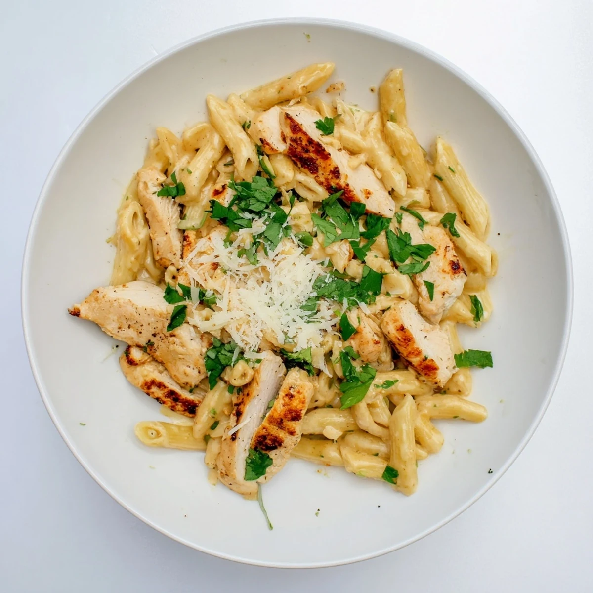 Steaming Honey Chipotle Chicken Pasta served in a rustic white bowl, highlighting the vibrant red sauce and melted Parmesan topping.