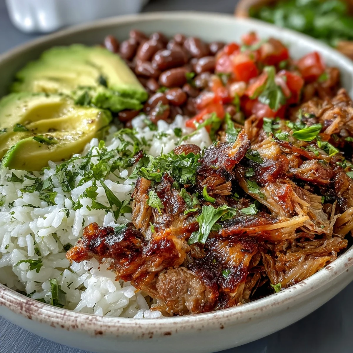 Savory Carnitas Bowl with lime wedges, pinto beans, and vibrant salsa, ready to serve.