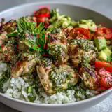 Bright, herbaceous pesto chicken bowl topped with crisp cucumber, red onion, and baby spinach leaves.