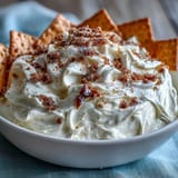 Viral 3-ingredient cheesecake dip in a bowl, topped with fresh berries for a colorful dessert.