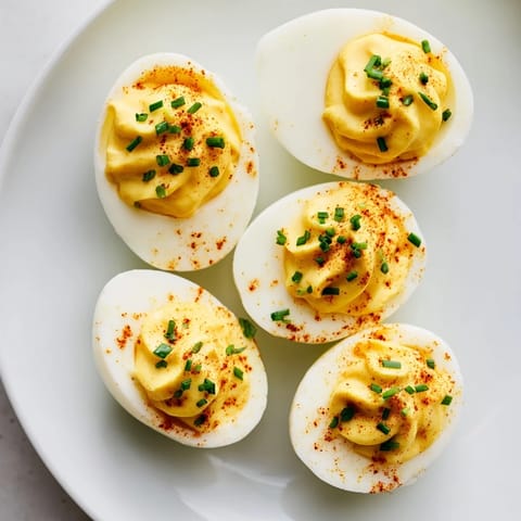 Creamy, tangy deviled eggs, perfect for parties, with bright paprika and fresh herb garnish.