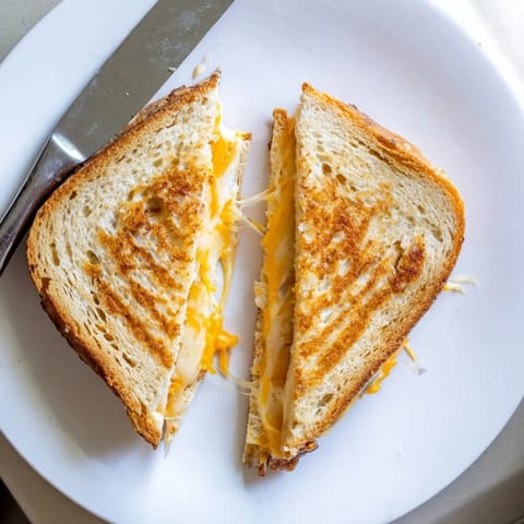 A close-up view shows gooey mozzarella oozing from the crispy butter-toasted sourdough Triple Cheese Sourdough Grilled Cheese.